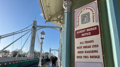 A sign says "All troops must break step when marching over this bridge"