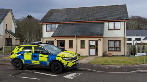 A police SUV parked outside a semi-detached property in Morrison Court, Dornoch. The vehicle has blue and yellow markings.