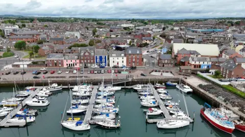 An aerial view of Arbroath Harbour. Sailing boats sit at the marina with a row of houses in the background