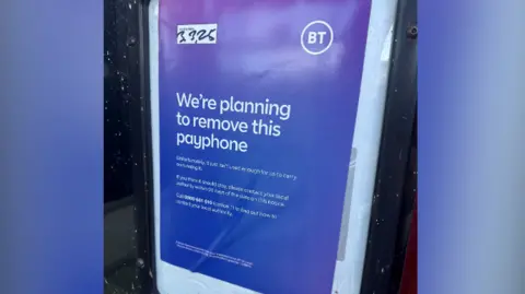 Alan Lewis A sign from BT saying "We're planning to remove this payphone". Smaller text underneath says "Unfortunately, it just isn't used enough for us to carry on running it"