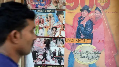 Getty Images An Indian cinemagoer walks past a poster of a screening of the popular Bollywood Hindi film 'Dilwale Dulhania Le Jayenge in 2014