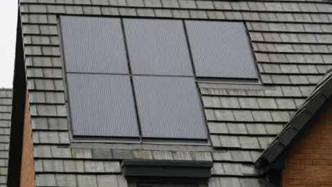 PA Media Five solar panels on the roof of a house.