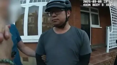 Met Police A man wearing a cycling helmet and glasses being arrested 