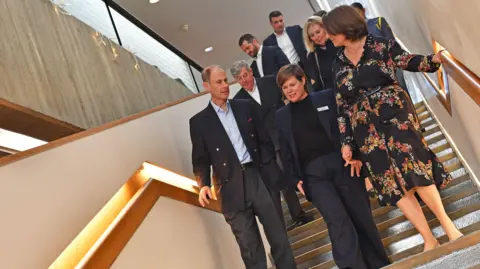 Lightbox Gallery Seven people walking down a flight of stairs. One of them is the Duke of Edinburgh