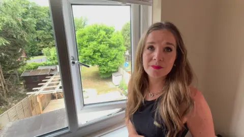 Kelly west in her house stood by the window