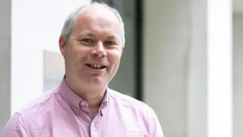 Alcohol Change UK Andrew Missell of Alcohol Change UK in Wales, wearing a pink shirt, smiling 