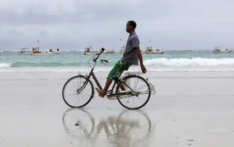 FEISAL OMAR/REUTERS A boy rides a bicycle on a beach.