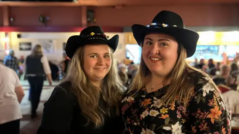 Two girls smiling in matching cowboy hats