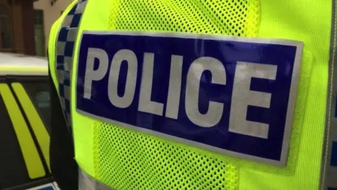BBC A hi-vis vest with POLICE written in capital letters against a blue background