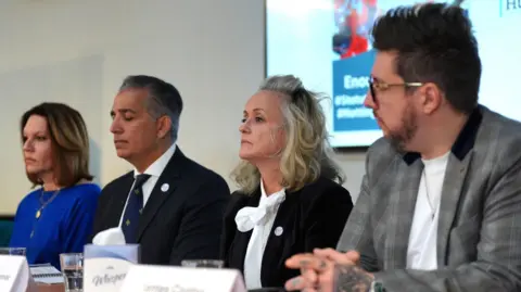 PA Media The families of the Nottingham attack victims sit at a table at a press conference