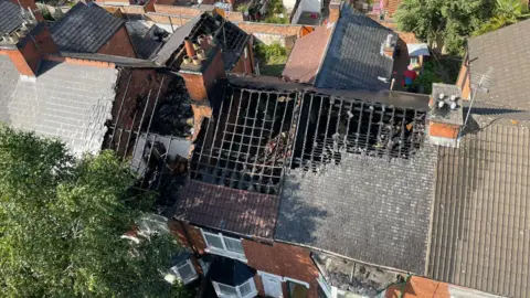 A drone view of damaged rooftops in a terraced street