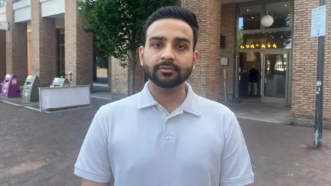 Sahil looks at camera, standing outside the block 
