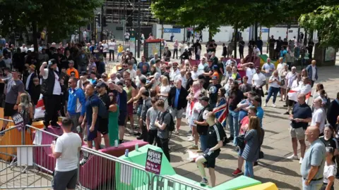 Dozens of people stand behind metal barriers during a far-right demonstration held on The Headrow in Leeds