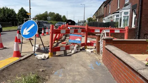 Malik Walton/BBC Wakefield Road, which has been fenced off following the flooding.