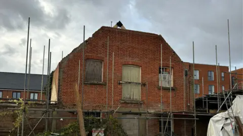 A red brick building covered in scaffolding. 