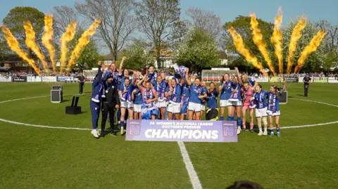 Ipswich Town women celebrate on the pitch after winning the league title. 