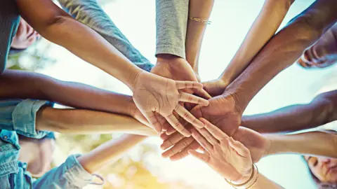 A close up of a group of people with their hands on top of each other