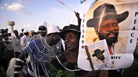 A supporter of President Salva Kiir holds up portraits of Kiir with the slogan "Freedom, Peace" during a political rally in Juba 