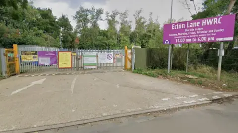 Google The exterior of the waste centre, with the metal gates closed. There is a huge purple sign on the right saying Ecton Lane HWRC / This site is open Monday, Thursday, Friday, Saturday and Sunday. 