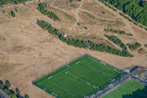 jasonhawkes.com Green football pitch surrounded by scorched grass