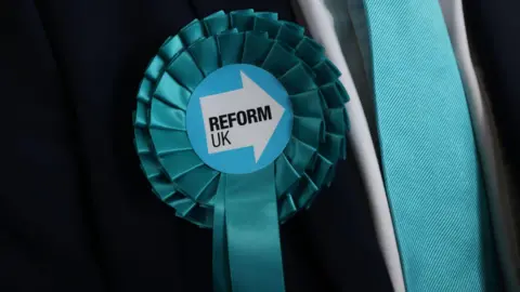 A turquoise rosette for the Reform Party pinned to a suit.