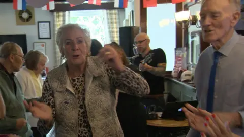 Members of the Forgotten Regulars dancing as singer performs in a pub