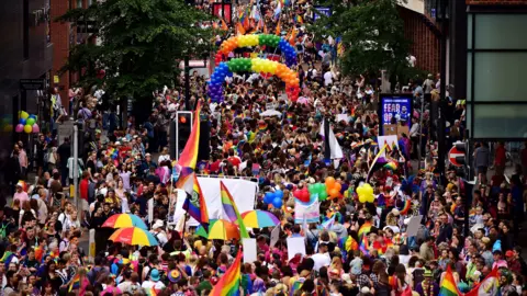 Dan Regan A wide view of the parade moving through central Bristol, with rainbow flags and umbrellas.