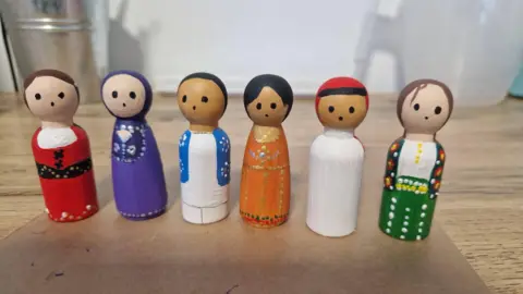 St. John's Pre School Six tiny wooden dolls- painted in colourful, different ethnic outfits.