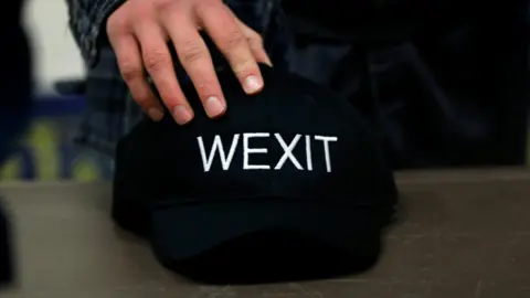 Reuters A supporter holds his Wexit hat at a rally for Wexit Alberta, a separatist group Alberta independence