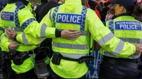 Police officers in a line with arms linking behind their back during a protest  