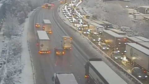 Traffic England/National Highways M25 between junction24 to 26 with traffic queuing due to snow and ice