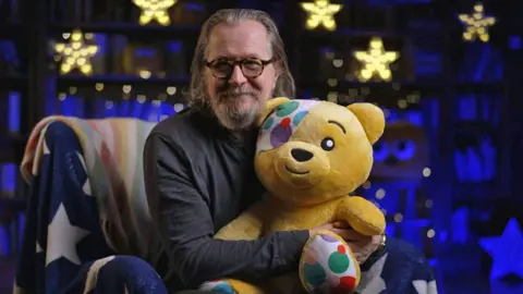 Gary Oldman in the CBBC Bedtime Story studio with Pudsey Bear on his lap