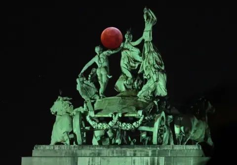 Reuters The moon seen beside a quadriga on top of the Cinquantenaire arch in Brussels