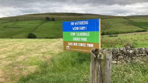 A campaign banner saying "No wuthering windfarm. Stop Calderdale Energy Park. Save our iconic moor."