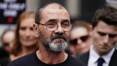 PA Media Andrew Malkinson wearing a black shirt standing outside next to a crowd.