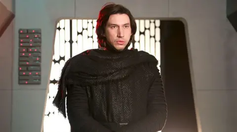 NBCUniversal/Getty Images Adam Driver in his Kylo Ren costume without the helmet stood in a set resembling the death star.