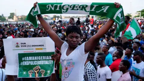 AFP A protester holds up a scarf with the same colours as the Nigerian national flag during a live concert at the Lekki toll gate in Lagos, on October 15, 2020, during a demonstration to protest against police brutality and scrapping of Special Anti-Robbery Squad (SARS).