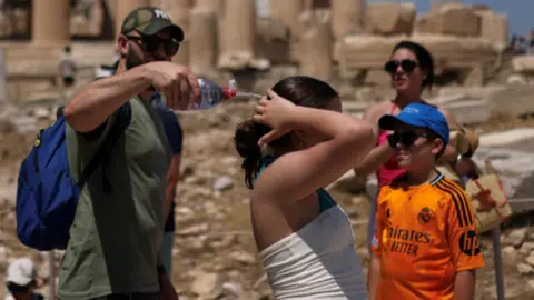 Tourists try to cool down during a visit to the Parthenon temple in Greece