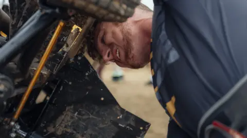 Harry George Hall Mechanic works on the knuckles on a lawn mower racing machine