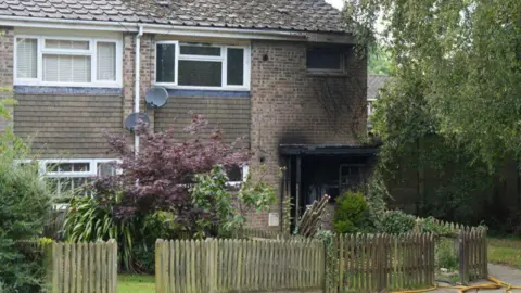 Eddie Mitchell A residential home is scorched after an arson attack. There is some green plants in front of the house.