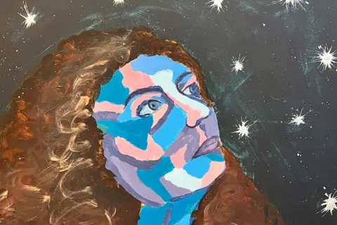 The courtesy of a single woman's self -portrait is a woman's face painted in blue, pink and purple with curly brown hair. He is looking up towards the night sky full of stars. 