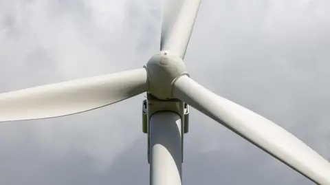 A close up of a wind turbine hub and its three blades.