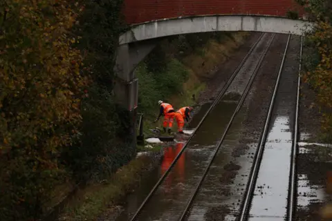 Getty Images Workers evacuate the water over the flooded railway in Romsey, southern England