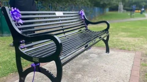 Lauren Carter/BBC A black iron bench in memory of Archie Battersbee has been unveiled in Priory Park, Southend