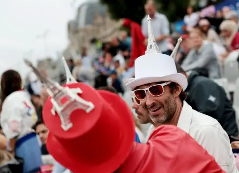  Claudia Greco/Reuters Spectators wearing top hats with Eiffel Towers on top sit in the stands