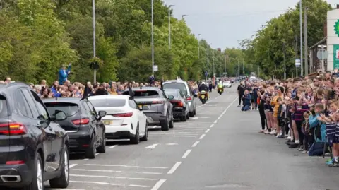 BBC/Oli Constable People line the route outside Featherstone Lions as the funeral procession goes past