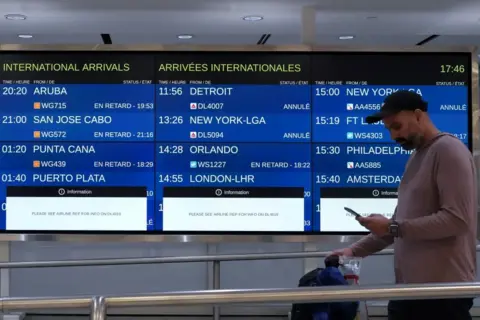 Reuters A passenger walks past airport timetables saying 'Delays' next to sceduled flights.