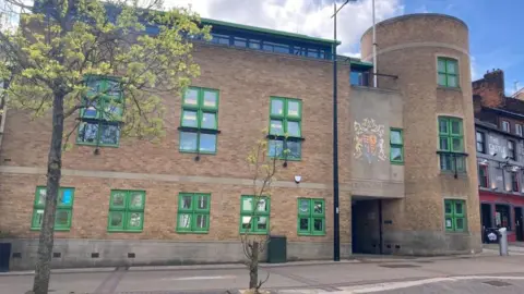 Brian Farmer/BBC Luton Crown Court: a brown brick building with green window frames. Two trees stand in the foreground. A sign over the entrance says "CROWN COURT"