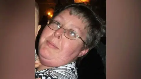 Police Scotland Woman - Elizabeth Watson - smiling astatine  camera, wearing glasses and wearing a achromatic  and achromatic  top.