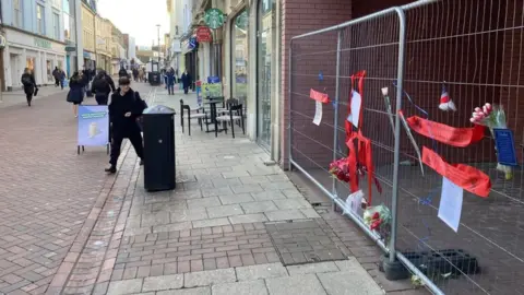 ANDREW WOODGER/ BBC Tributes on wire fencing, in Westgate Street in Ipswich